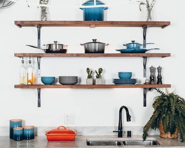 Wooden shelfs with dishes on white background in kitchen.